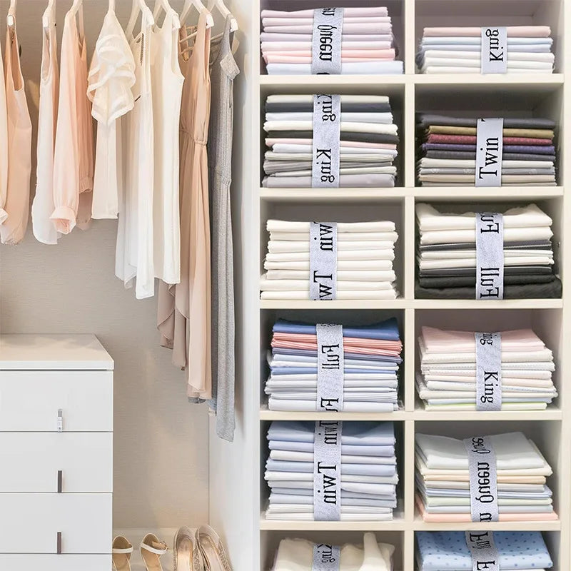 A white shelving unit organizes various colored bed sheets and linens using elastic straps.