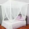 A large four-door mosquito net draped over a bed, featuring sheer white fabric and pink accents.