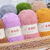 A collection of fluffy velvet yarn in various shades including purple pink orange and green stacked in a wooden basket