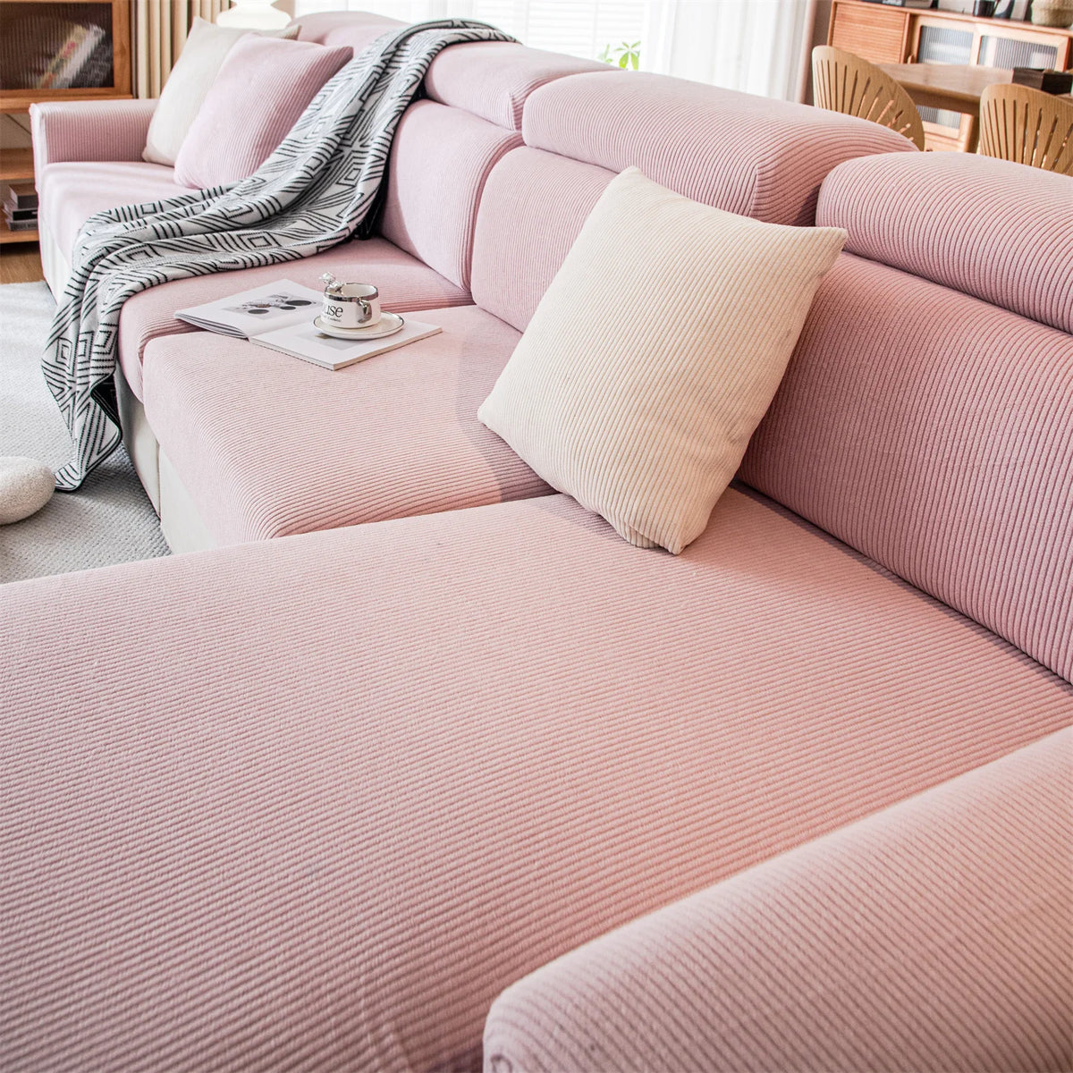 A pink removable jacquard seat cushion cover on a sofa with a striped throw and a cream pillow.