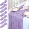 A purple lilac cheesecloth table runner draped over a white tablecloth set for a meal.