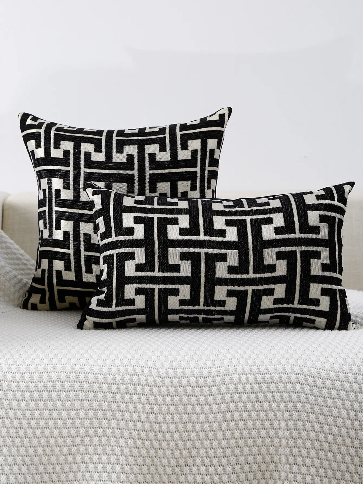 Black and white geometric patterned throw pillows resting on a light gray textured surface.