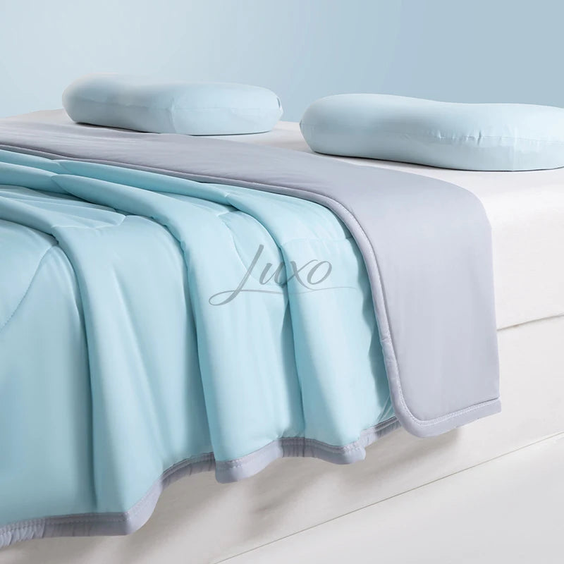 Light blue and gray ice silk summer cooling blanket draped over a white surface.