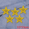 Five gold glitter star patches are placed on a light blue denim fabric.