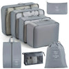 A set of gray travel storage organizers including a large zippered case, multiple storage boxes, and a drawstring bag.
