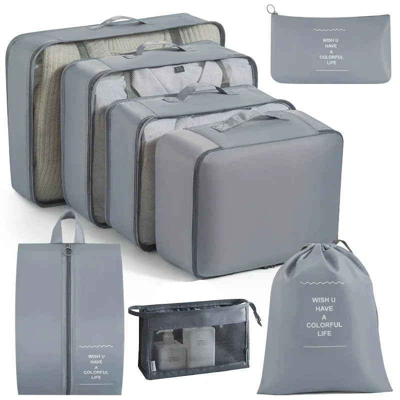 A set of gray travel storage organizers including a large zippered case, multiple storage boxes, and a drawstring bag.