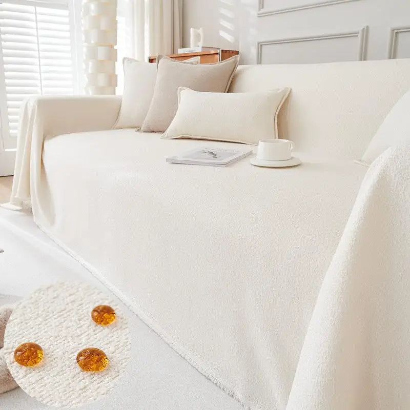 A cream-colored sofa covered with a white anti-scratch slipcover and decorative pillows.