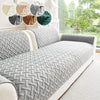 A gray quilted sofa cushion with a white trim is displayed next to decorative fabric swatches.