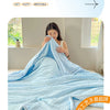 A woman is relaxing with a light blue breathable waffle quilt in a bright room.