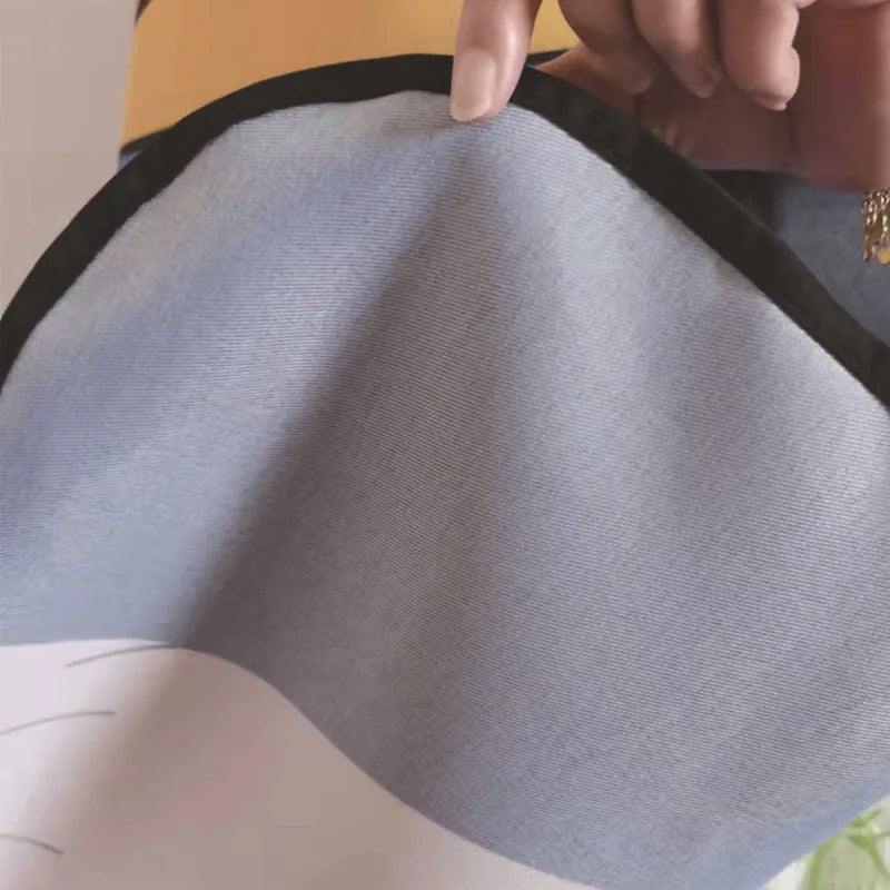 A hand is adjusting a light blue fabric apron with black trim.