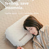A woman rests her head on a natural-colored inflatable pillow while lying on a textured blanket.