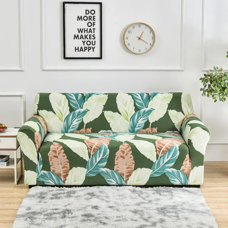 A green floral print elastic sofa cover protector displayed on a light wood floor.