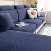 A deep blue woven sofa seat cushion cover with a textured pattern and a white decorative pillow on a light-colored sofa.