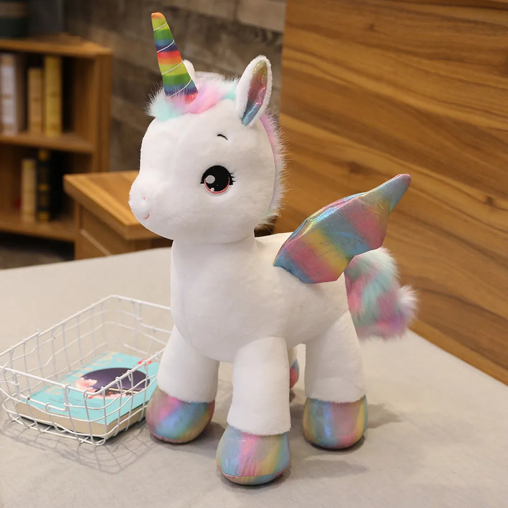 A white plush unicorn toy with a rainbow horn and multicolored ears sitting on a table.
