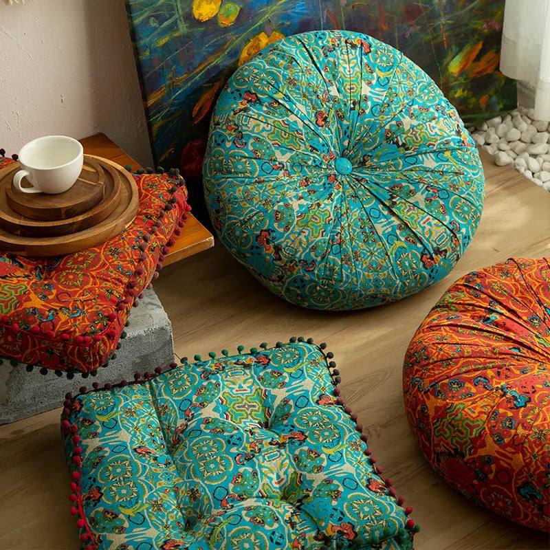 A vibrant teal and green bohemian cotton linen throw cushion resting on a wooden surface.