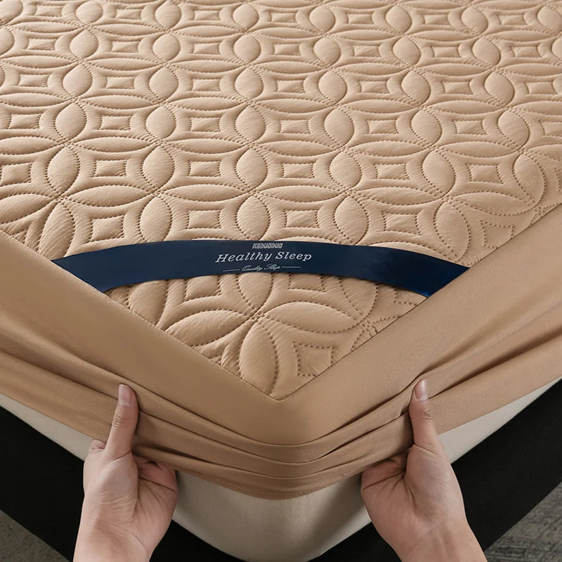 A beige quilted mattress protector is shown being held by hands, featuring the Healthy Sleep brand.