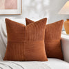 A set of four brown corduroy throw pillow covers with a vertical ribbed texture and patchwork design resting on a white sofa.