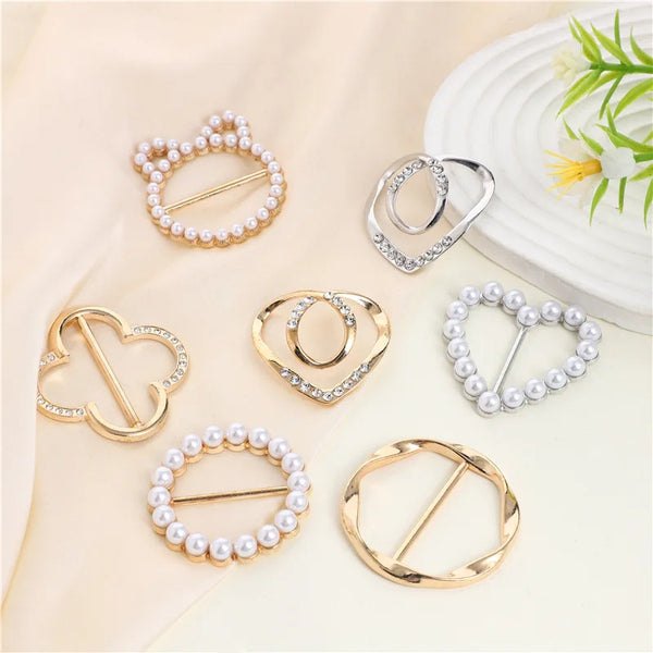 A collection of elegant gold and silver metal ring clips and hoops with pearl accents displayed on a light fabric.