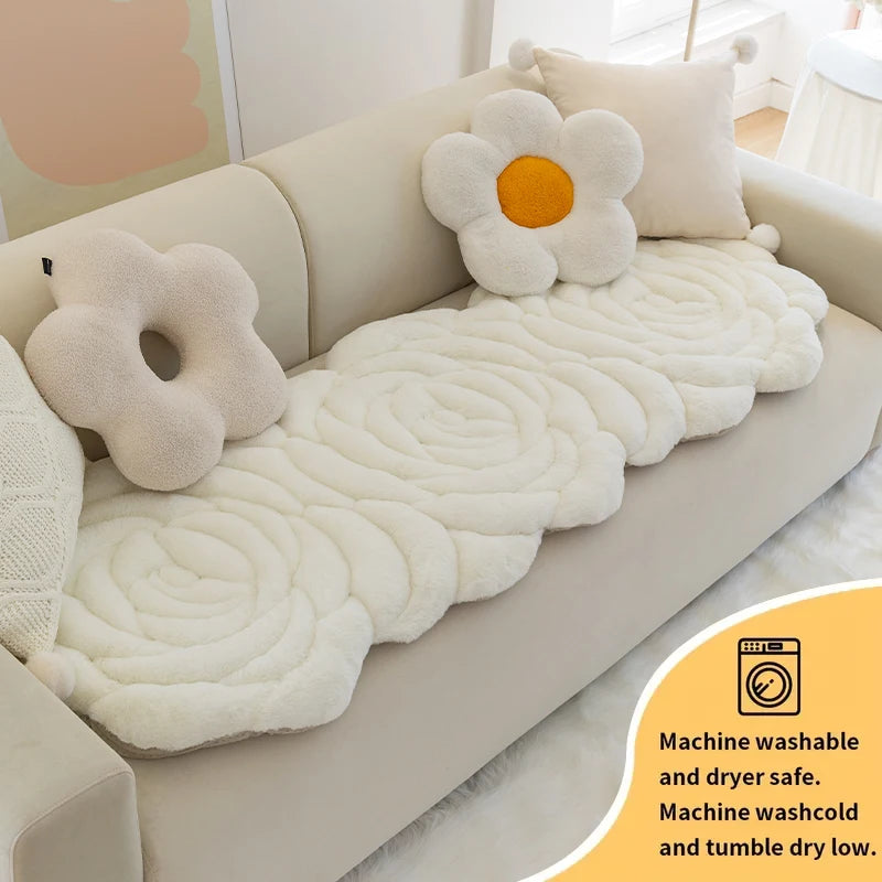 A white, fluffy mat is placed on a beige sofa, featuring a daisy design and labeled for machine wash and dryer use.