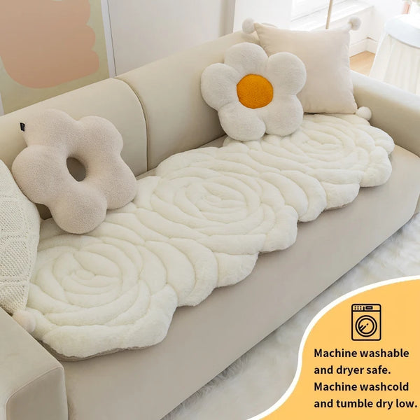 A white, fluffy mat is placed on a beige sofa, featuring a daisy design and labeled for machine wash and dryer use.