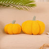 Two bright yellow felt pumpkins with green stems resting on a beige fabric surface.
