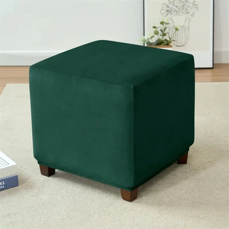A dark emerald green velvet ottoman slipcover placed on a light carpet.