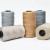 Four spools of hand knitting and crochet cord in various shades of gray and beige yarn