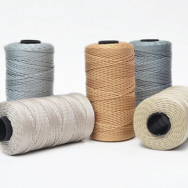 Four spools of hand knitting and crochet cord in various shades of gray and beige yarn