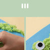 A hand is pressing green felt onto a blue craft mat to create a felt animal character.