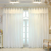 White double-layer blackout curtains with sheer overlay hanging in a window frame.