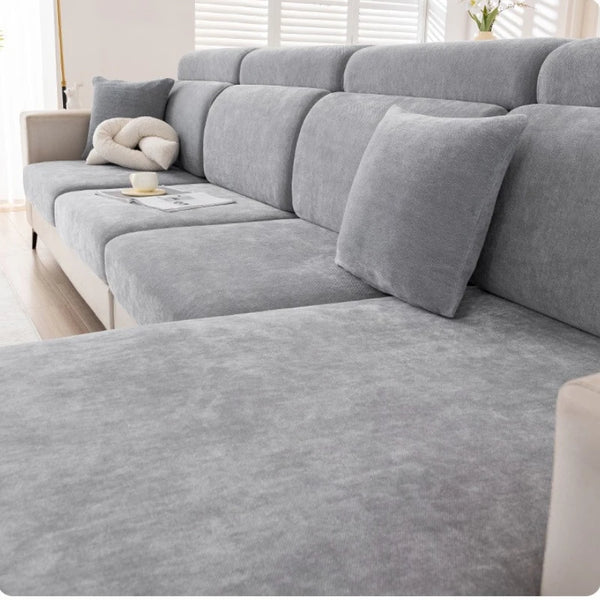 A light gray universal elastic sofa cover with a full backrest shown in a living room setting.