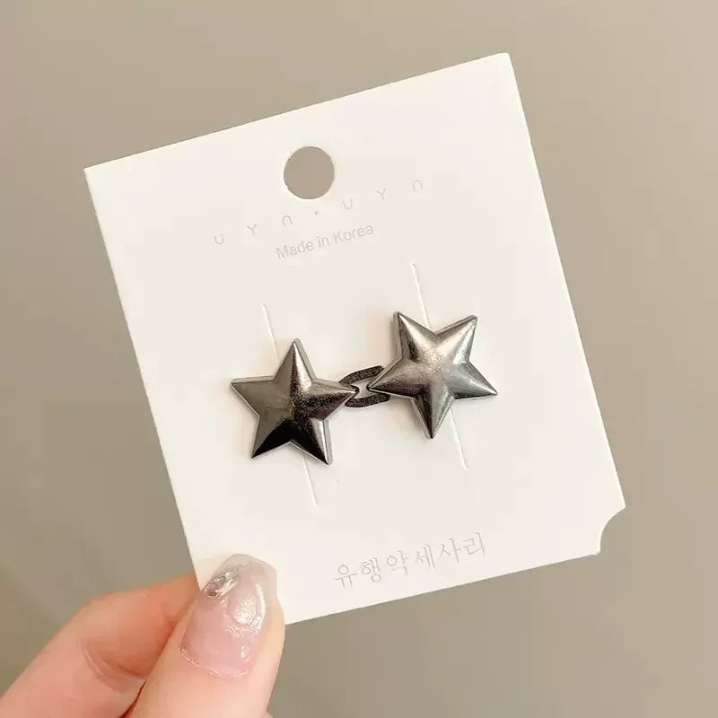 A pair of silver star-shaped metal brooch pins displayed on a white card.