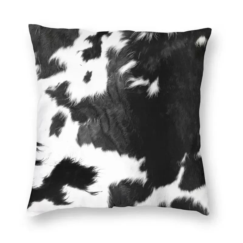 A square cushion cover featuring a black and white cowhide print.