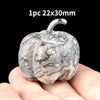 A natural stone pumpkin figurine with marbled gray and white patterns is held in a hand.