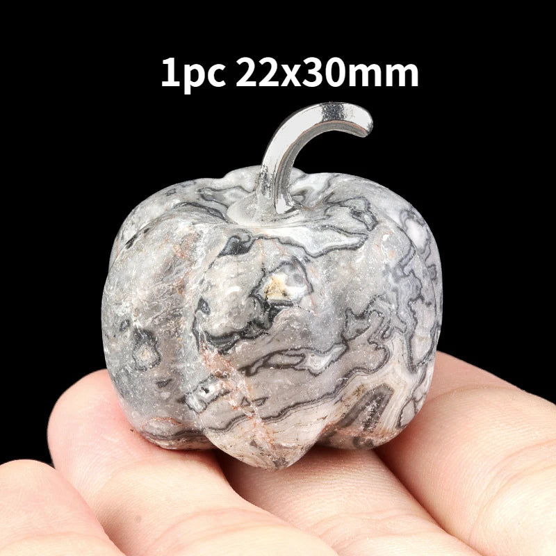 A natural stone pumpkin figurine with marbled gray and white patterns is held in a hand.
