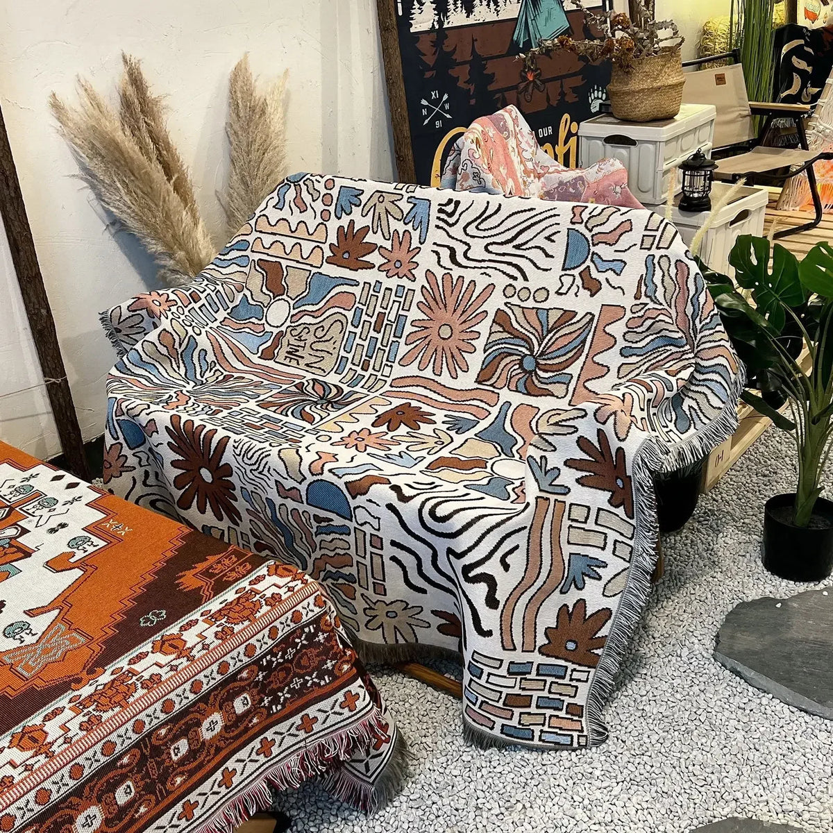 A bohemian geometric throw blanket featuring earthy tones and abstract patterns draped on a sofa.