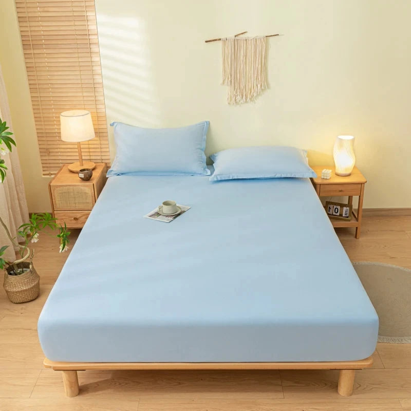A light blue fitted sheet set on a wooden bed with matching pillows and bedside lamps.