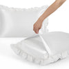 A hand is opening a white ruffled satin pillowcase, showing the silky envelope closure.