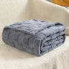 A folded gray checkered fleece throw blanket resting on a cream-colored, fluffy surface.
