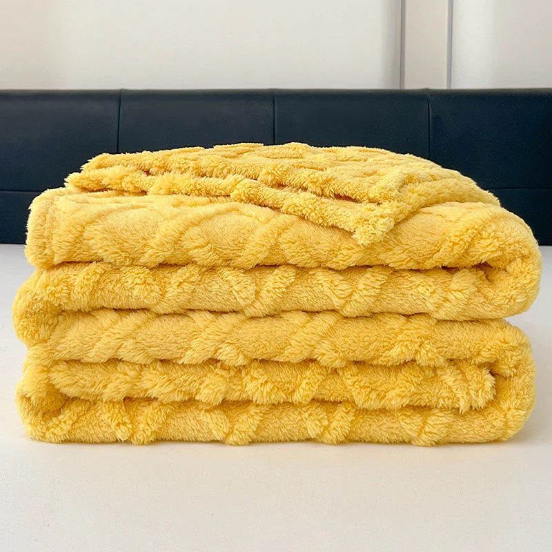 A stack of bright yellow ultra-soft coral fleece blankets folded neatly on a white surface.