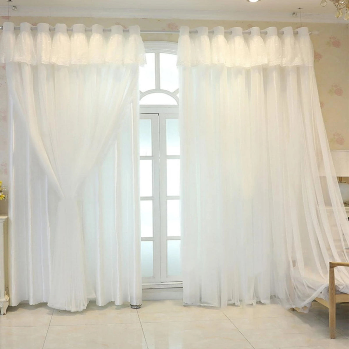 White sheer double-layer curtains with gathered fabric framing a tall arched window.