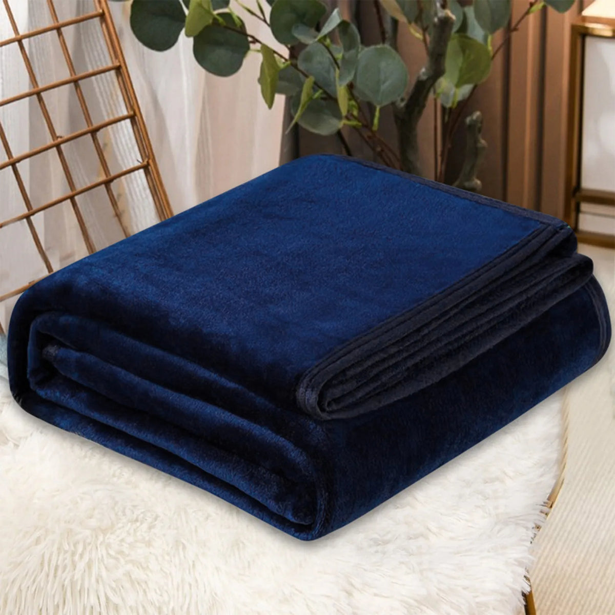 A dark navy blue velvet throw blanket folded neatly on a white fluffy surface.