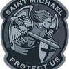 A circular patch featuring a winged figure holding a sword on a shield with the text Saint Michael Protect Us