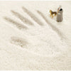 A paw print in white snow or fluff with a small dog and a person standing nearby.