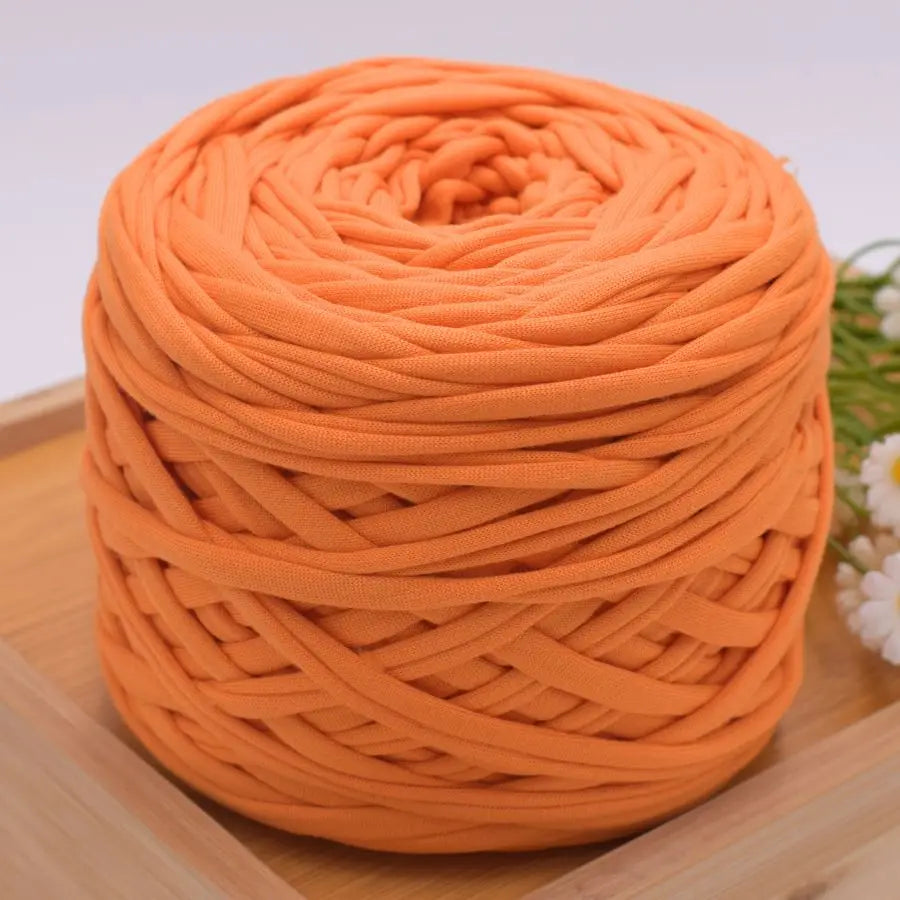 A ball of bright orange craft yarn made of 100% polyester for knitting and DIY projects.