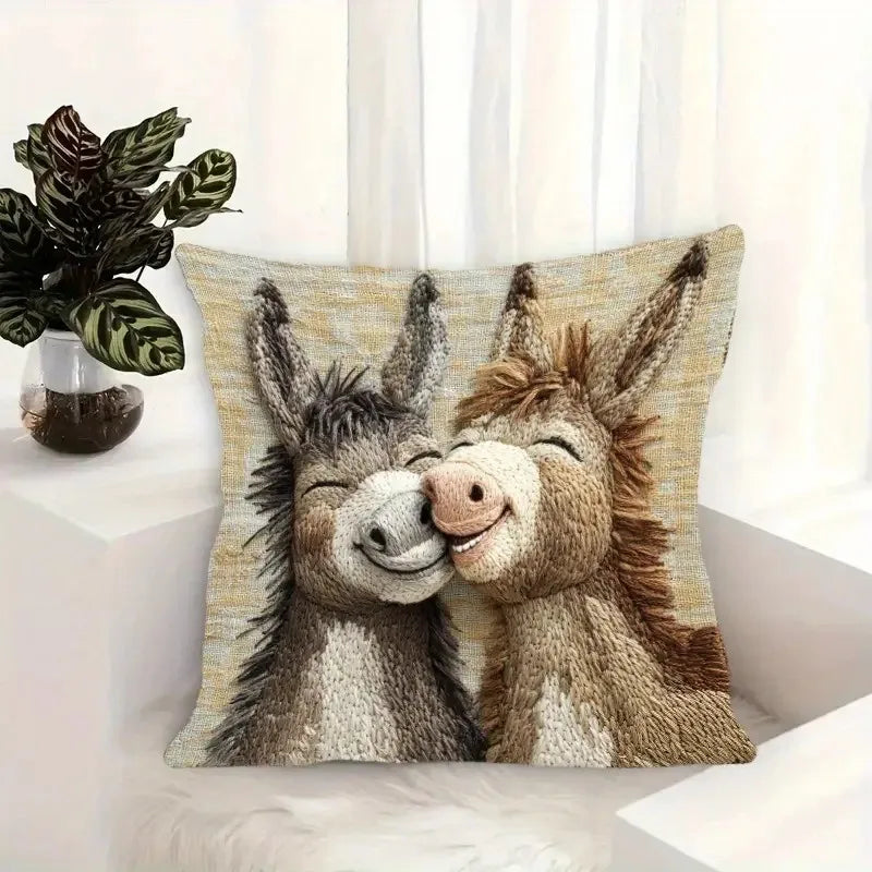 A beige and brown textured pillow cover featuring a cartoon illustration of two affectionate donkeys.