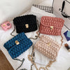 A collection of five textured fabric bags in black, pink, blue, and beige with gold metal clasps displayed on white fabric.
