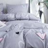 Gray bedding set featuring white and pink heart prints on a duvet cover and pillowcases.