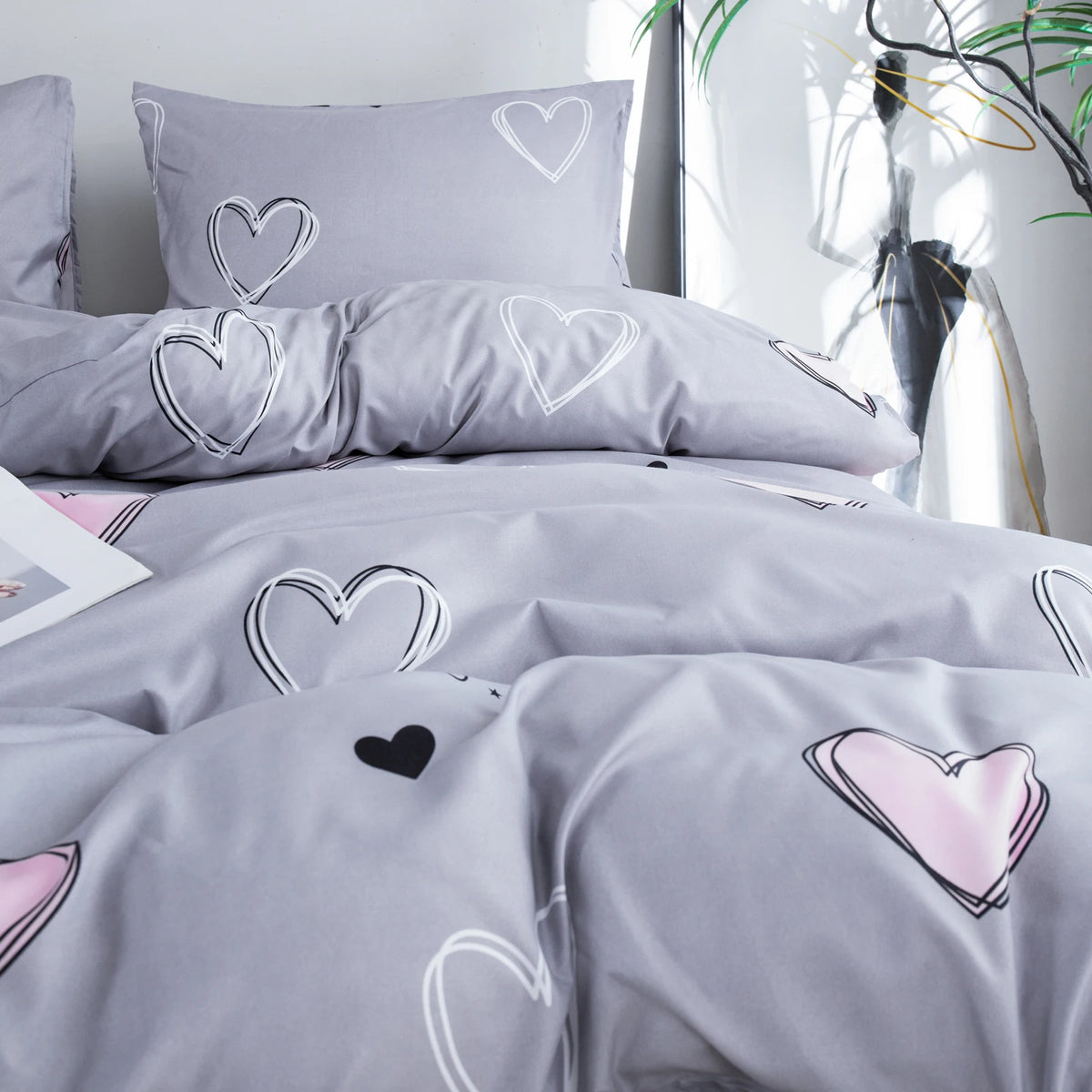 Gray bedding set featuring white and pink heart prints on a duvet cover and pillowcases.