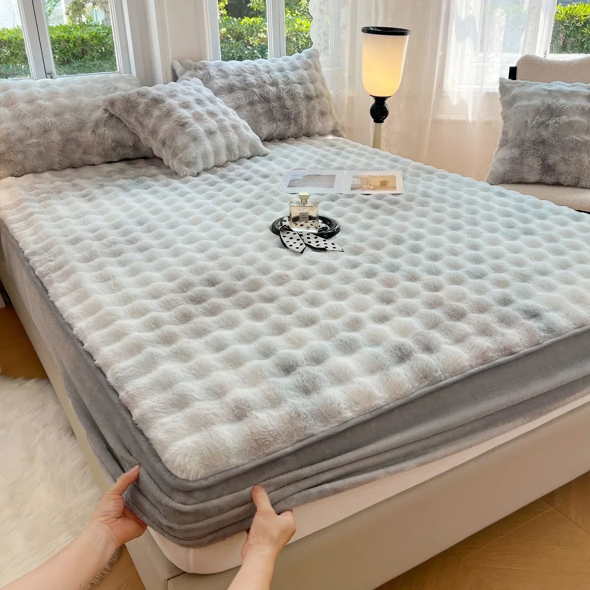 A fitted sheet set with faux rabbit fur covering a bed, displayed on a white surface.